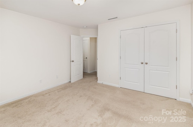 unfurnished bedroom featuring baseboards, visible vents, a closet, and carpet floors