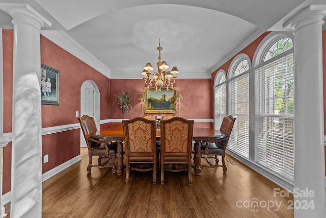 dining space featuring hardwood / wood-style floors, decorative columns, ornamental molding, and an inviting chandelier