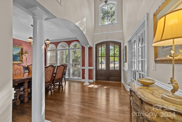 foyer entrance with french doors, a towering ceiling, hardwood / wood-style flooring, and ornate columns