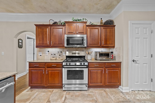 kitchen featuring tasteful backsplash, crown molding, light stone countertops, and stainless steel appliances