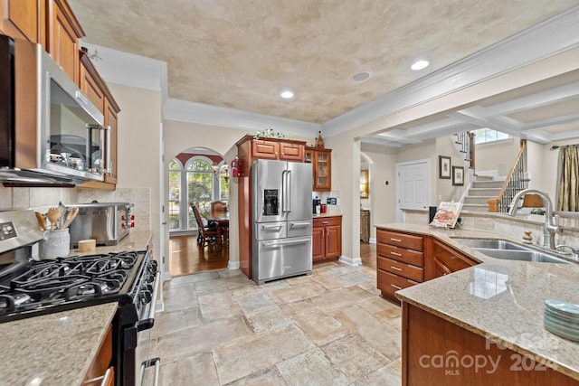 kitchen with light stone countertops, backsplash, stainless steel appliances, crown molding, and sink