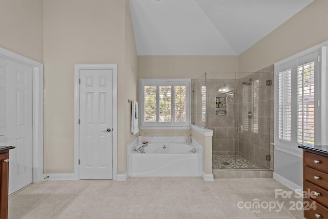 bathroom with tile patterned flooring, vanity, vaulted ceiling, and shower with separate bathtub