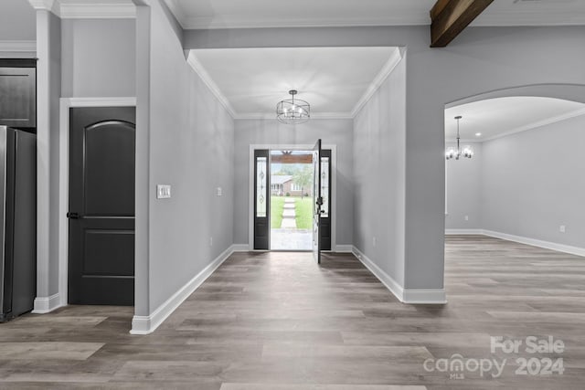 foyer entrance with light hardwood / wood-style floors, crown molding, beam ceiling, and a chandelier