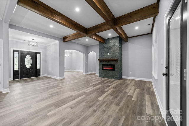 entrance foyer featuring beamed ceiling, a stone fireplace, light wood-type flooring, and coffered ceiling