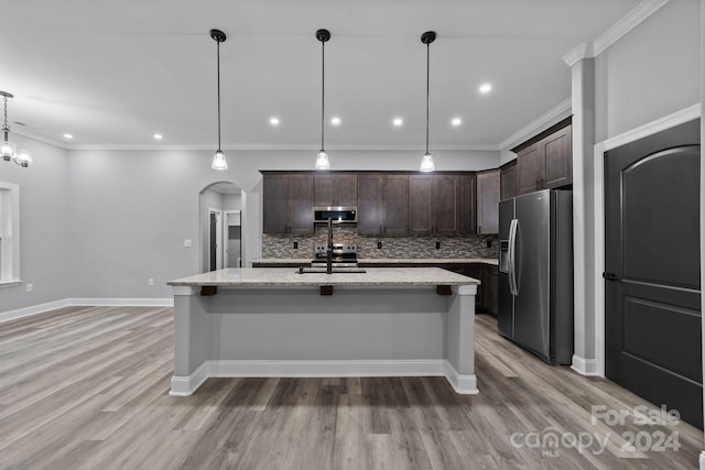 kitchen featuring backsplash, a center island with sink, decorative light fixtures, dark brown cabinets, and stainless steel appliances