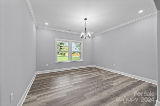 empty room featuring hardwood / wood-style floors, ornamental molding, and a notable chandelier