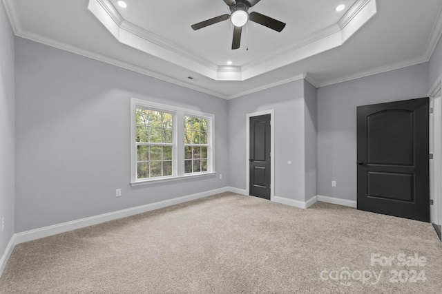 unfurnished bedroom featuring a raised ceiling, ceiling fan, crown molding, and light colored carpet