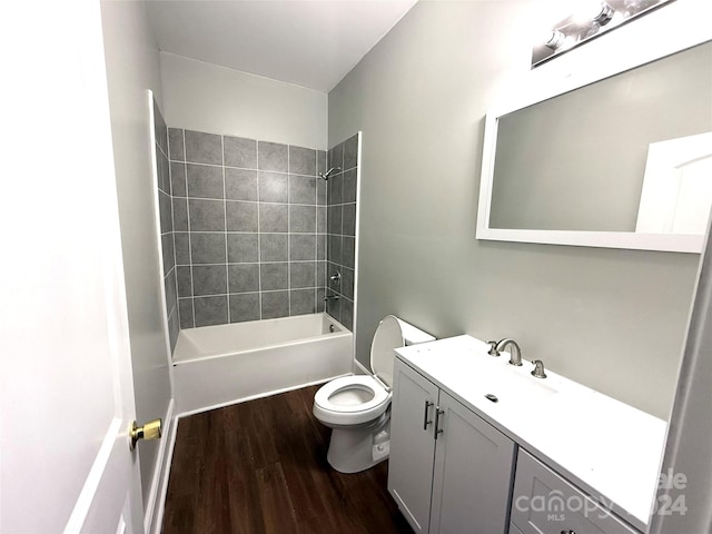 full bathroom with hardwood / wood-style floors, tiled shower / bath combo, toilet, and vanity