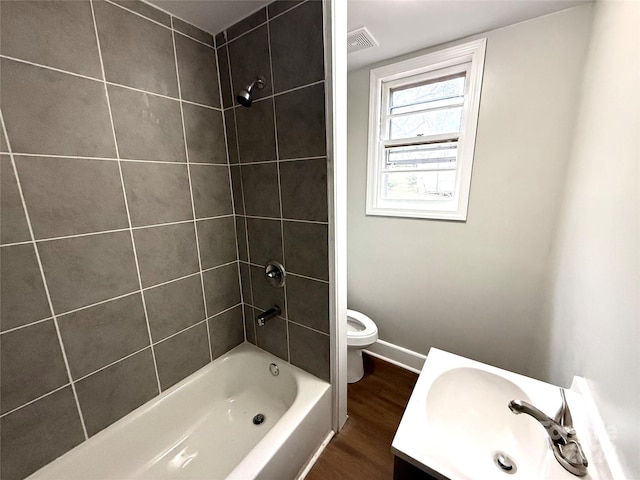 full bathroom featuring tiled shower / bath combo, toilet, wood-type flooring, and vanity