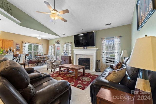 tiled living room with a fireplace, a textured ceiling, ceiling fan, and a healthy amount of sunlight