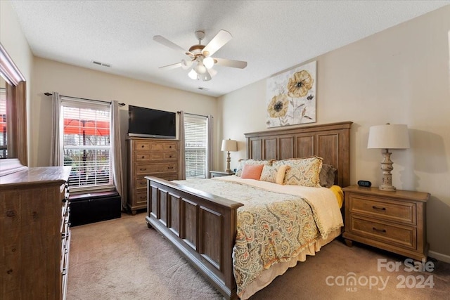 carpeted bedroom with multiple windows, ceiling fan, and a textured ceiling