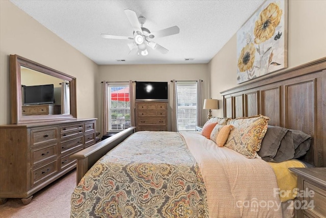 carpeted bedroom featuring multiple windows, a textured ceiling, and ceiling fan