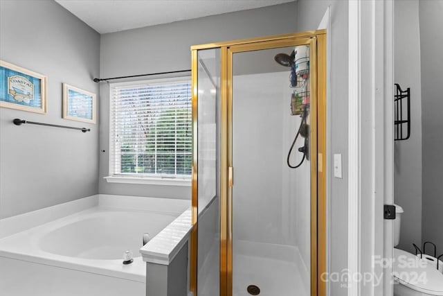 bathroom with toilet, a textured ceiling, and separate shower and tub