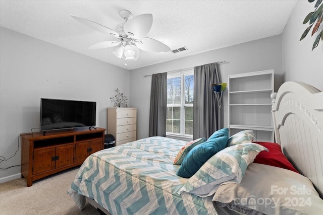 carpeted bedroom featuring ceiling fan and a textured ceiling