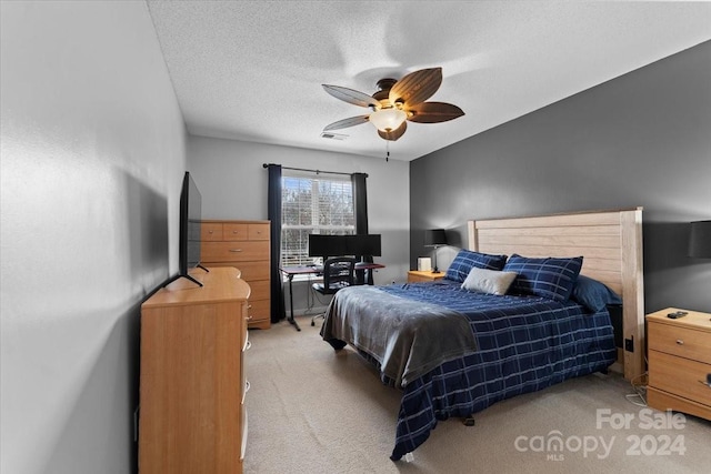 bedroom featuring ceiling fan, light colored carpet, and a textured ceiling