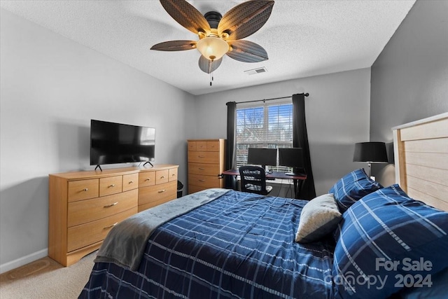 carpeted bedroom featuring ceiling fan and a textured ceiling