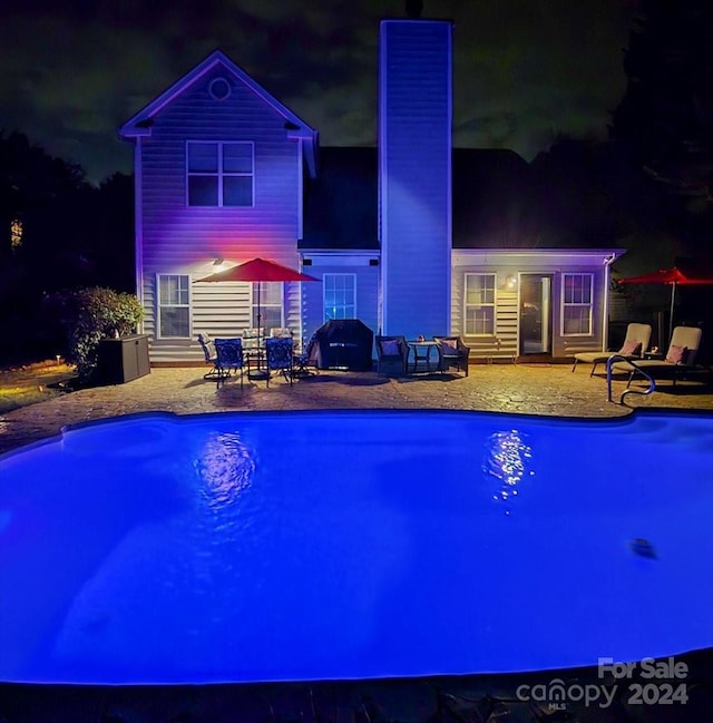 pool at twilight featuring a patio area and a grill