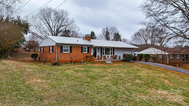 ranch-style home featuring aphalt driveway, brick siding, a chimney, a front yard, and crawl space