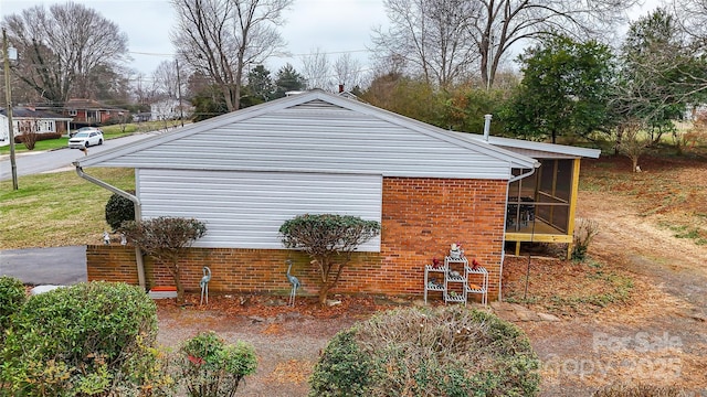 view of side of property with a sunroom and brick siding