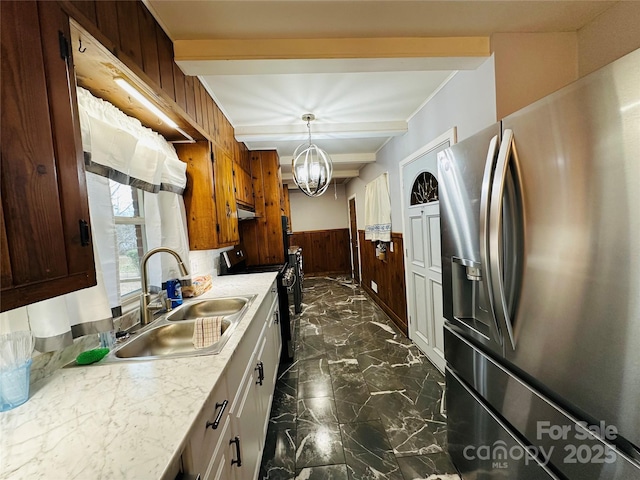 kitchen featuring marble finish floor, stainless steel refrigerator with ice dispenser, electric range oven, wainscoting, and a sink