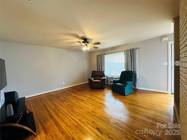 sitting room featuring a ceiling fan, baseboards, and wood finished floors