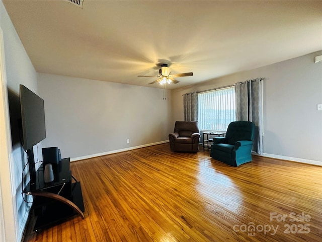 living area with ceiling fan, baseboards, and wood finished floors