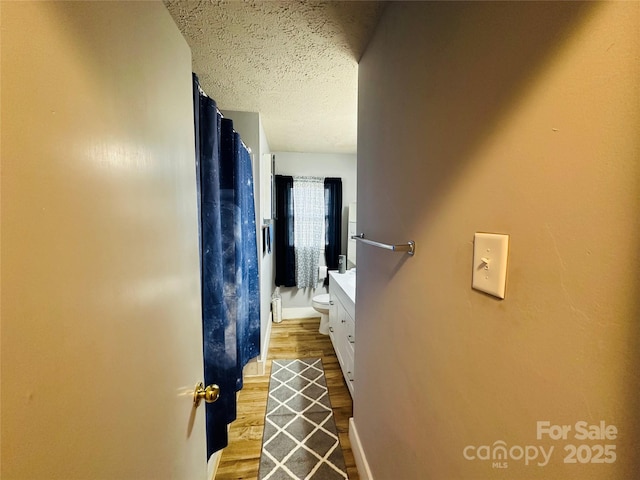 bathroom with toilet, wood finished floors, curtained shower, a textured ceiling, and vanity