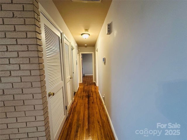 hallway with dark wood-type flooring and baseboards