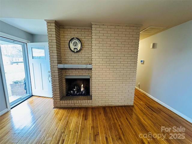 unfurnished living room with wood-type flooring, a fireplace, visible vents, and baseboards