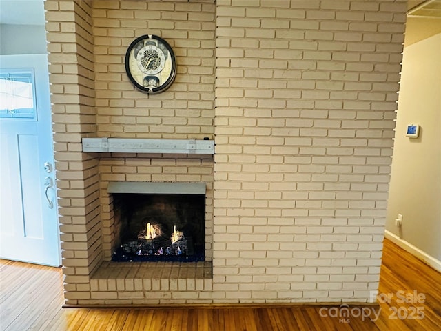 interior details featuring a fireplace, baseboards, and wood finished floors