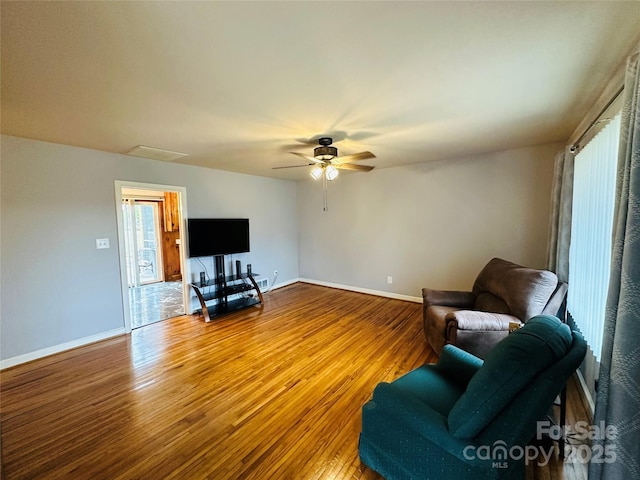 sitting room with ceiling fan, baseboards, and wood finished floors