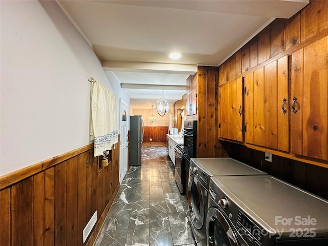 laundry room with laundry area, wooden walls, a wainscoted wall, marble finish floor, and separate washer and dryer