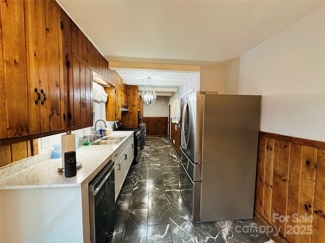 kitchen with a notable chandelier, a wainscoted wall, stainless steel appliances, a sink, and marble finish floor