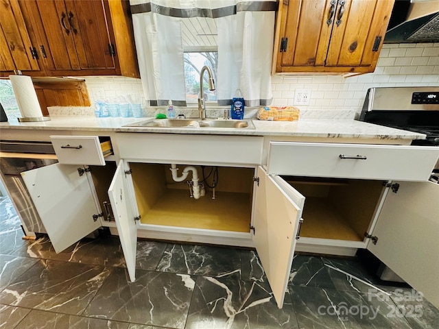 details featuring decorative backsplash, brown cabinets, light stone countertops, range hood, and a sink