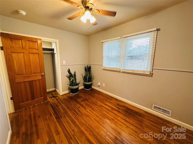 unfurnished bedroom with a ceiling fan, visible vents, baseboards, a closet, and hardwood / wood-style floors