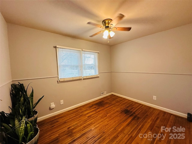 unfurnished room featuring dark wood-style floors, visible vents, a ceiling fan, and baseboards