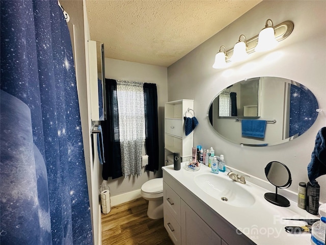 bathroom featuring a textured ceiling, toilet, wood finished floors, vanity, and a shower with curtain