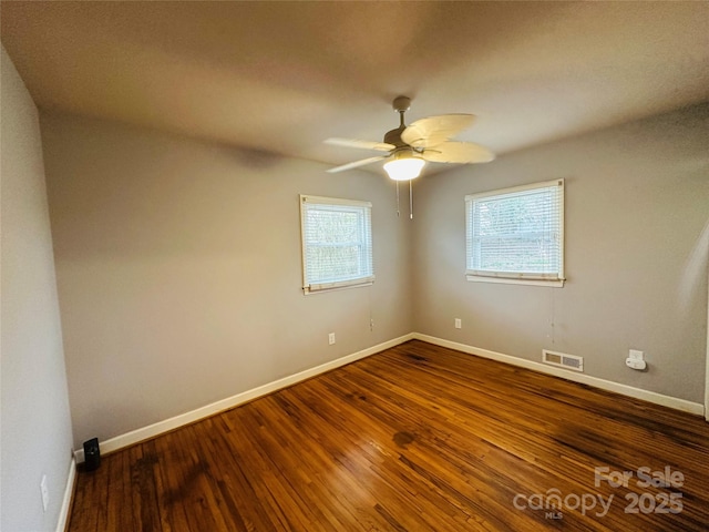 unfurnished room featuring baseboards, visible vents, ceiling fan, and wood finished floors