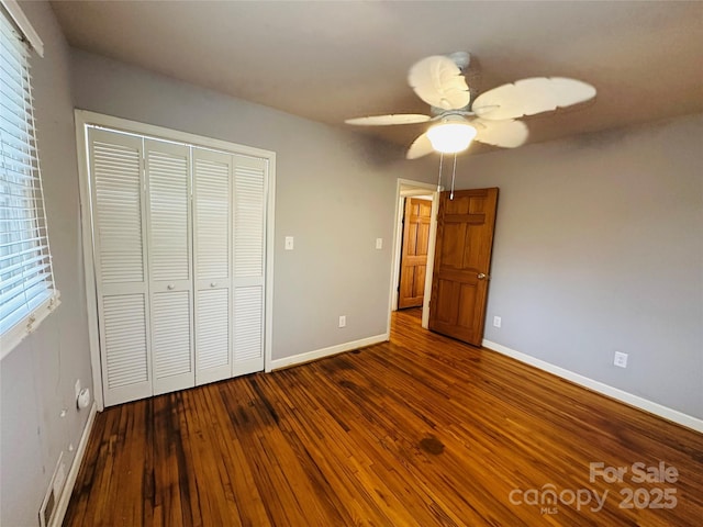 unfurnished bedroom with ceiling fan, hardwood / wood-style floors, a closet, and baseboards