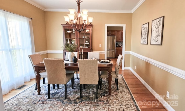 dining space with dark wood-type flooring, a chandelier, and ornamental molding