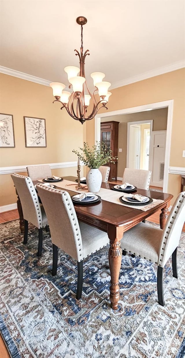 dining space featuring ornamental molding, a notable chandelier, and wood-type flooring