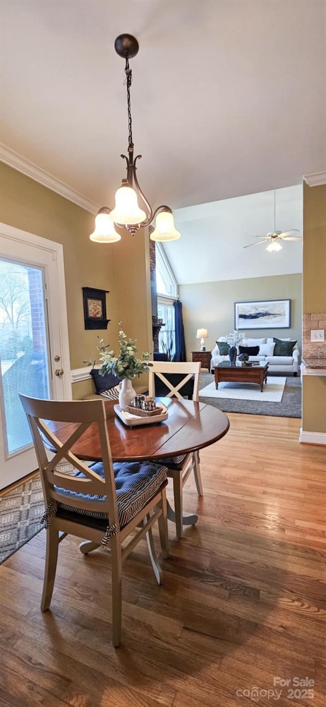 dining room with wood-type flooring, vaulted ceiling, ceiling fan, and crown molding