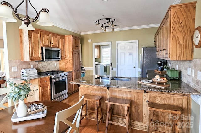 kitchen featuring sink, stainless steel appliances, tasteful backsplash, kitchen peninsula, and hardwood / wood-style flooring