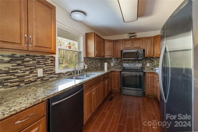 kitchen with light stone countertops, decorative backsplash, dark hardwood / wood-style flooring, stainless steel appliances, and sink