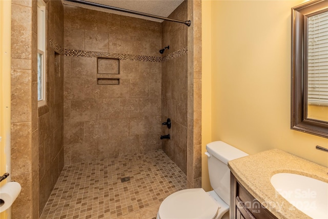 bathroom featuring a tile shower, vanity, and toilet