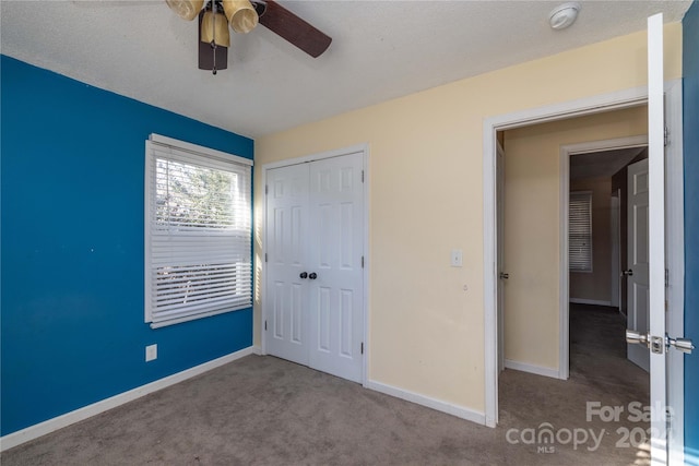 unfurnished bedroom featuring carpet, ceiling fan, a textured ceiling, and a closet