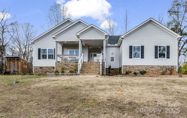 view of front facade featuring an outbuilding, a porch, crawl space, and a front yard