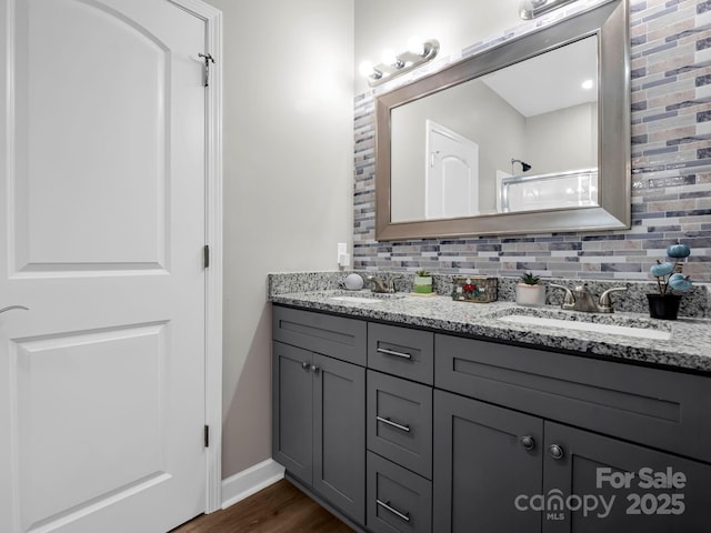 full bathroom featuring double vanity, wood finished floors, a sink, and decorative backsplash