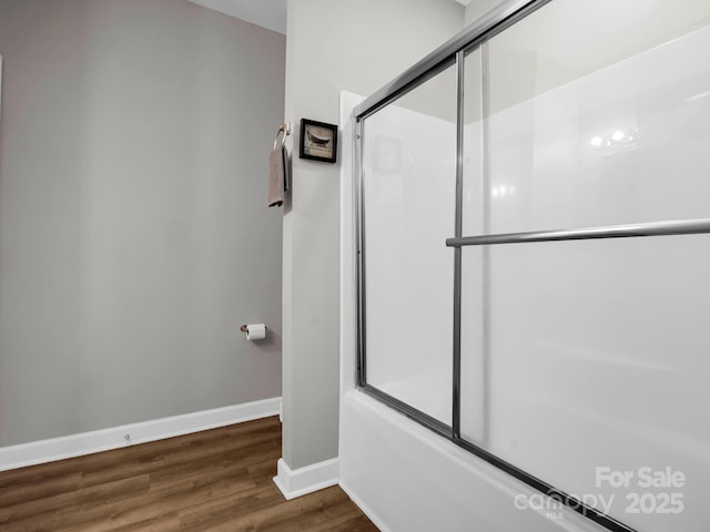 bathroom with shower / bath combination with glass door, baseboards, and wood finished floors