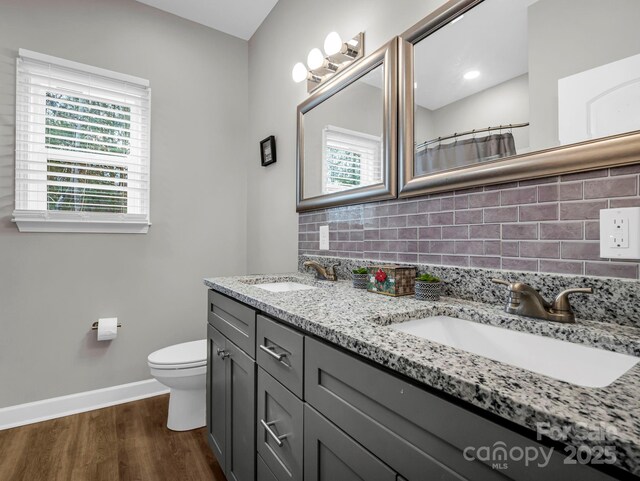 bathroom featuring vanity, backsplash, hardwood / wood-style floors, and toilet